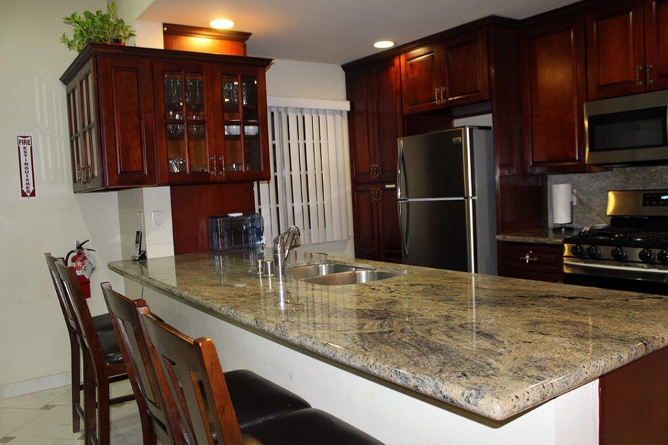 A modern kitchen featuring granite countertops and dark wooden cabinetry.