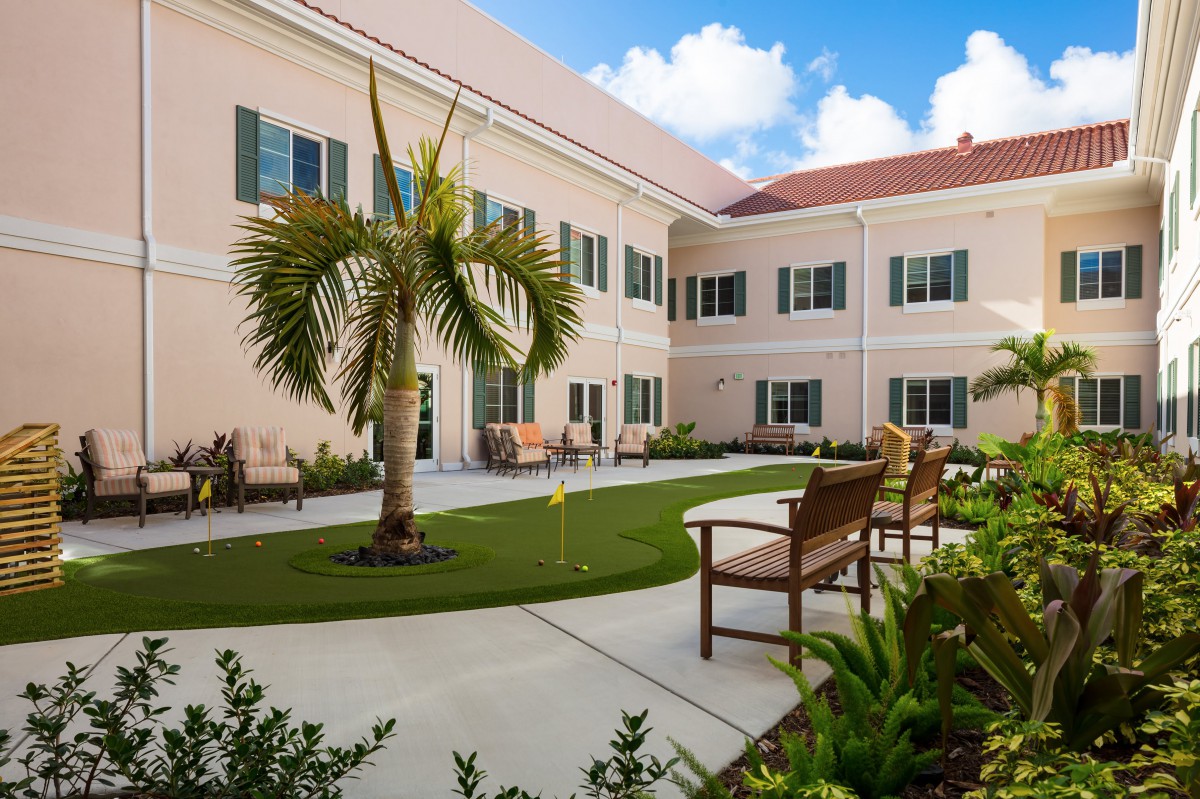 A well-maintained courtyard with a palm tree and benches in front of a building.