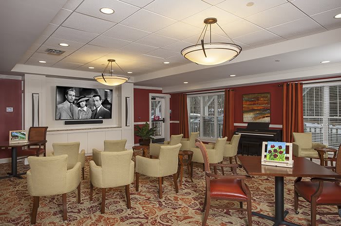 A cozy conference room with comfortable seating and a television displaying a black-and-white movie.