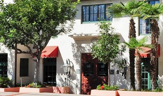 A charming building with a red awning, surrounded by trees and plants.