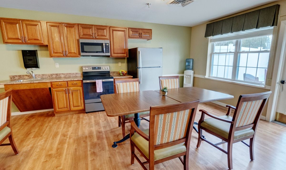 A cozy kitchen and dining area featuring wooden cabinets, a table with chairs, and standard kitchen appliances.