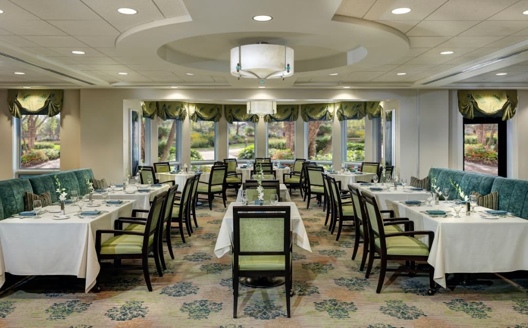 A beautifully arranged restaurant dining room with elegantly set tables and large windows.