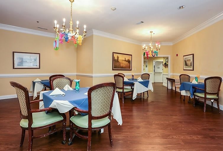 A beautifully set dining room with elegant chandeliers and blue-accented table settings.