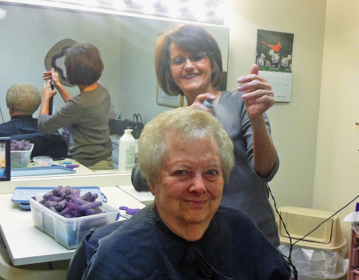 A cheerful client enjoying her salon experience while the hairdresser works on her hair.