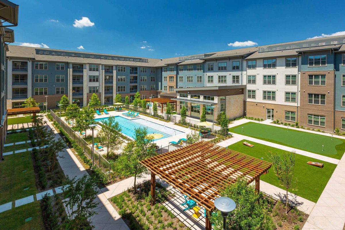 A modern apartment complex featuring a pool and well-maintained outdoor landscaping.