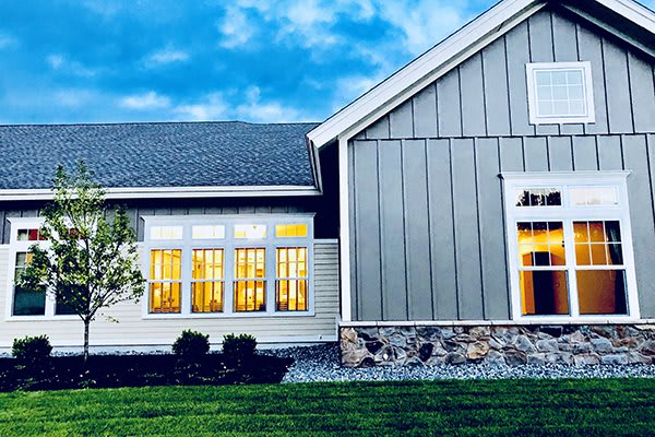 A modern house exterior with illuminated windows against a twilight sky.