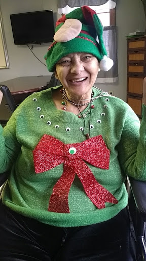 A cheerful woman dressed in a festive green Christmas sweater with a red bow, showcasing the holiday spirit.