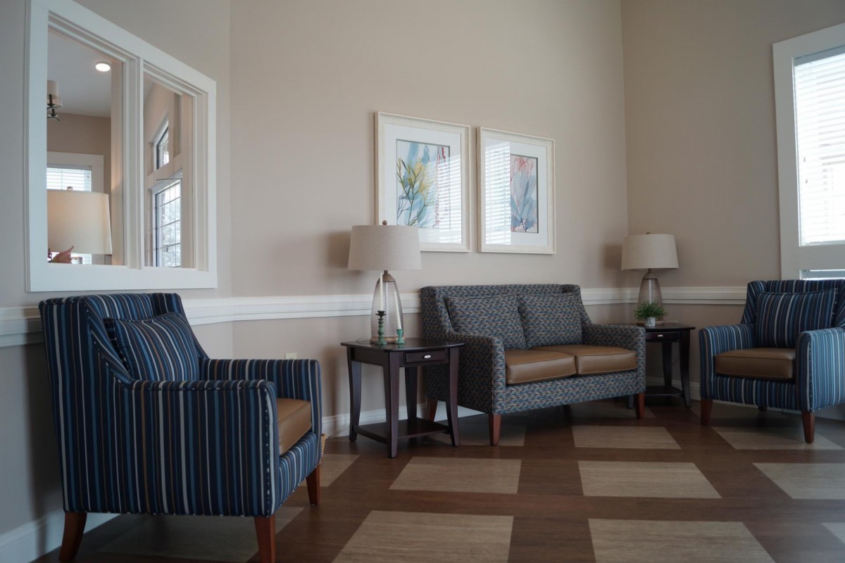 A cozy living room with a sofa, armchairs, lamps, and wall art.