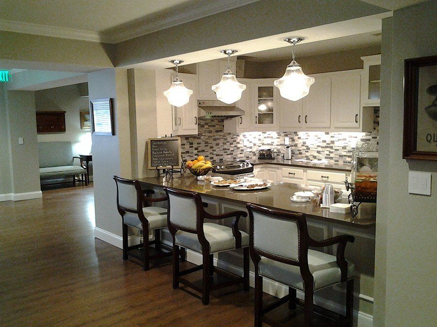 A modern kitchen featuring a stylish island with bar stools, elegant pendant lighting, and a patterned tile backsplash.
