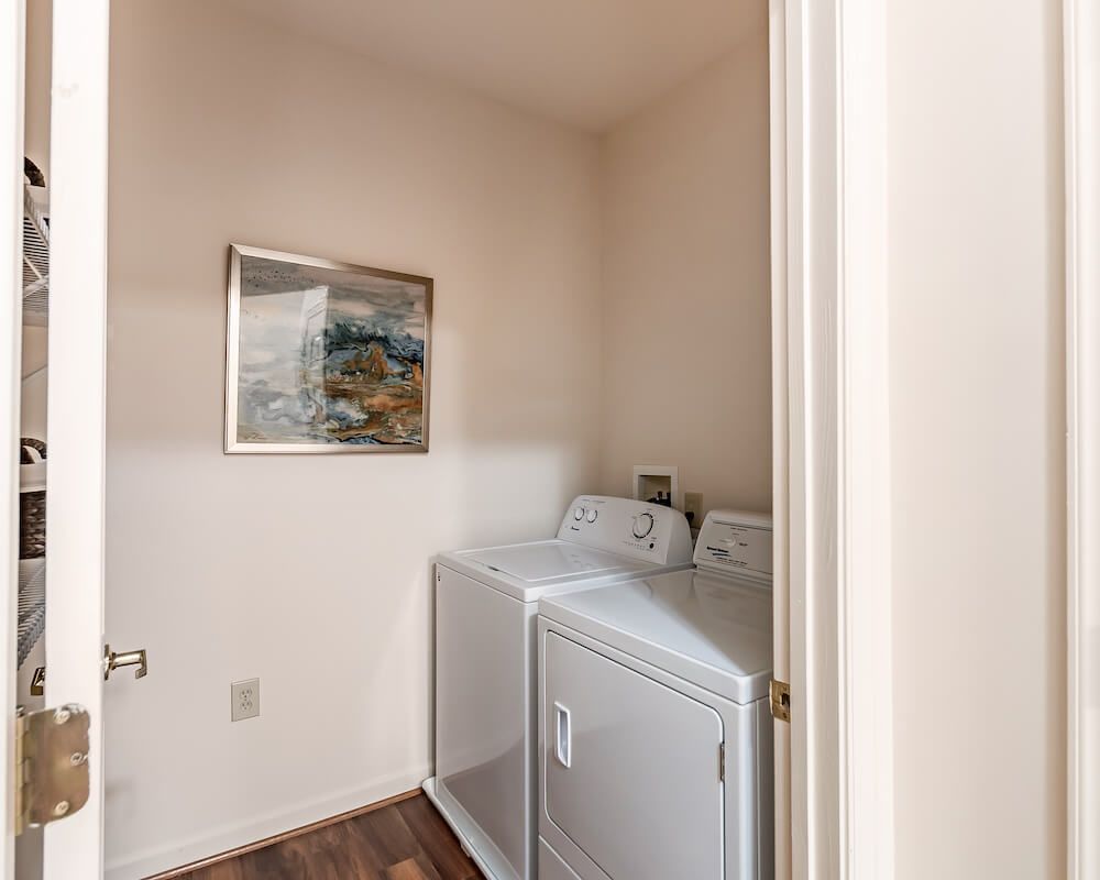 A compact laundry room featuring a washer and dryer with a decorative painting on the wall.