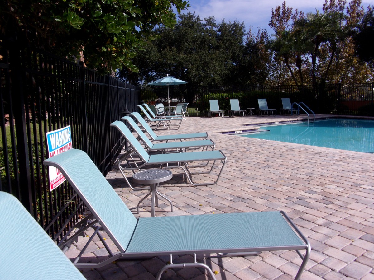A serene outdoor pool area with sun loungers and an umbrella, perfect for relaxation.