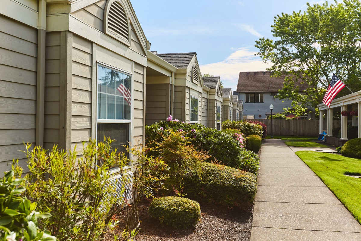 A row of suburban houses with well-maintained gardens lining a sidewalk.