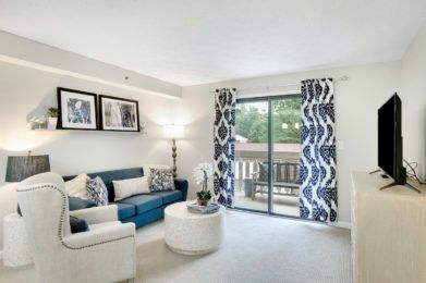 A modern living room with a blue sofa, patterned curtains, and stylish decor.
