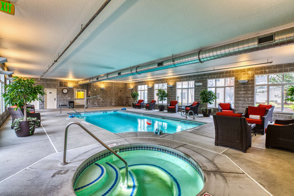 A spacious indoor swimming pool area with a hot tub and comfortable seating, providing a luxurious relaxation space.