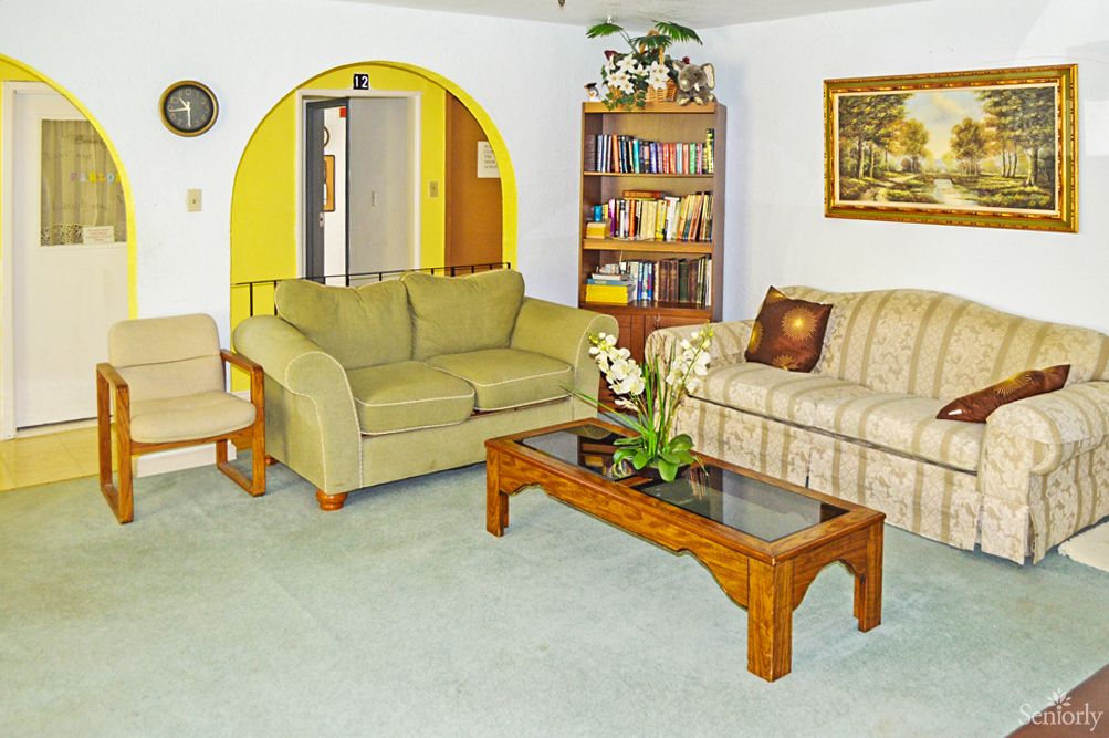 A cozy living room with sofas, a coffee table, and a bookshelf against a yellow-accented archway.