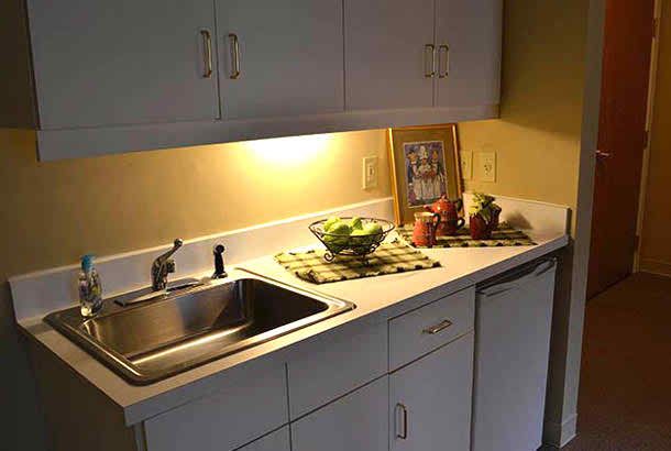 A kitchen counter with a sink, cabinetry, and a fruit bowl under soft lighting.