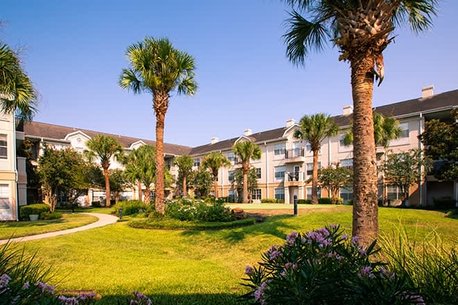 A well-landscaped apartment complex with palm trees on a sunny day.