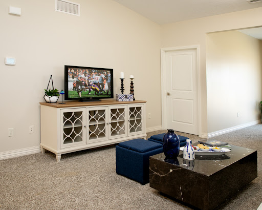 A cozy living room featuring a television, elegant furniture, and a neutral color palette.