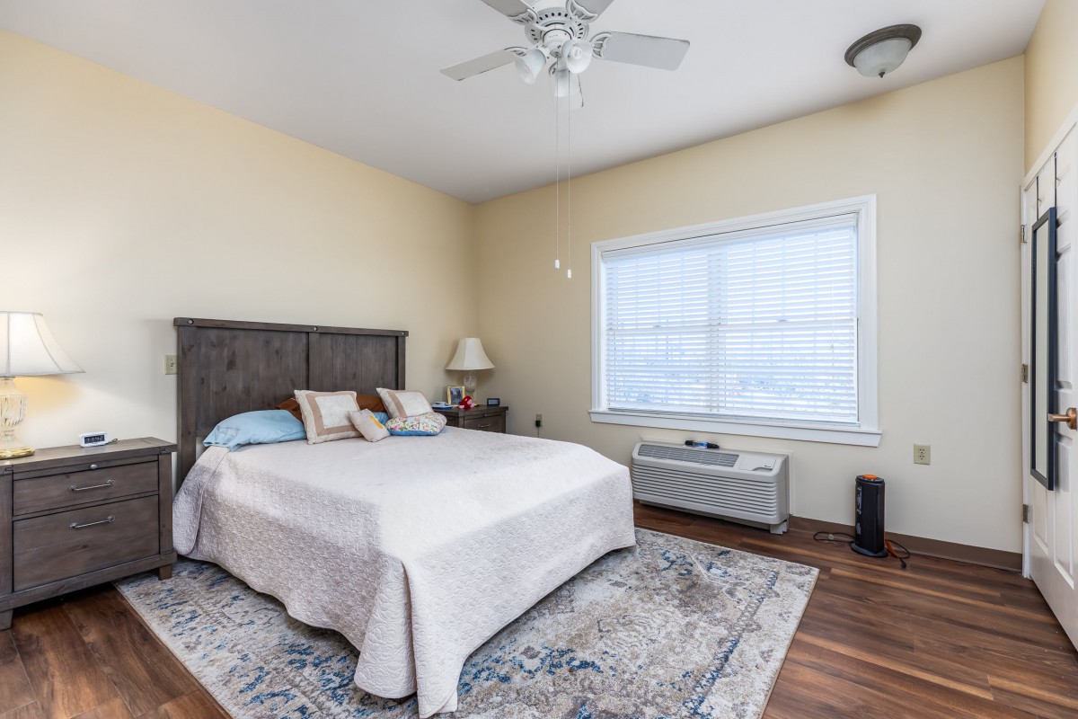 A cozy bedroom with a large bed, soft lighting, and a window allowing natural light.