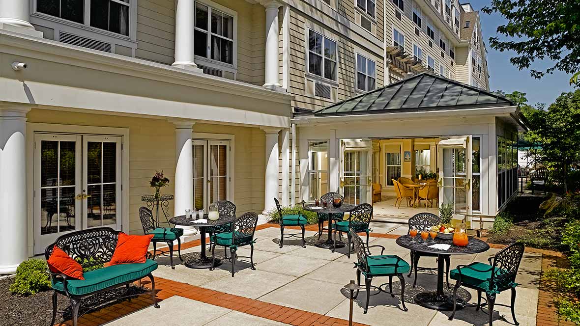 A sunny patio area with tables and chairs outside a building.