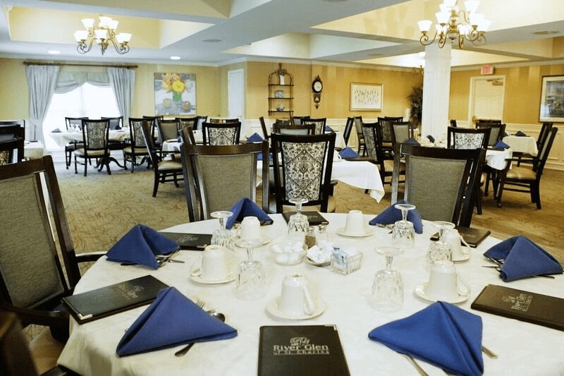 Elegant dining room with tables set for service, featuring blue napkins and stylish chairs.