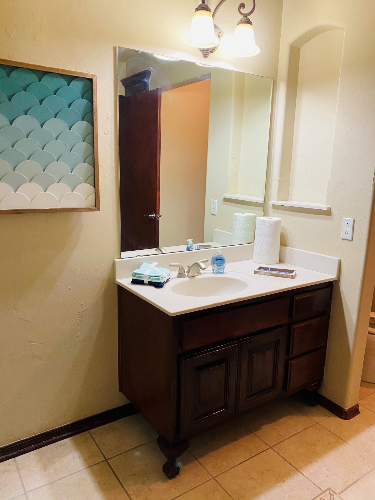 A clean bathroom vanity with a sink, mirror, and wall art.