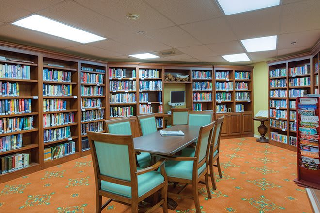 A cozy library with bookshelves, a table, and chairs for reading.