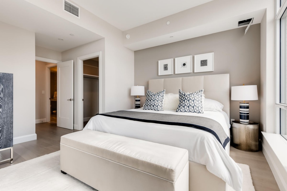 A modern bedroom with a neutral color palette, featuring a neatly made bed and contemporary decor.