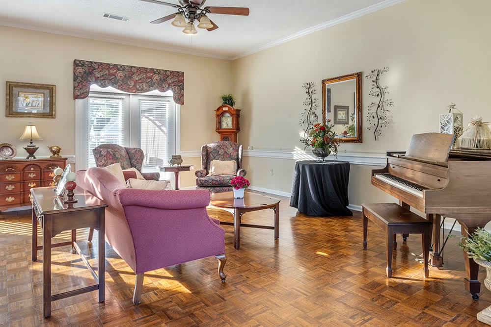A cozy living room featuring elegant furniture, a piano, and abundant natural light.