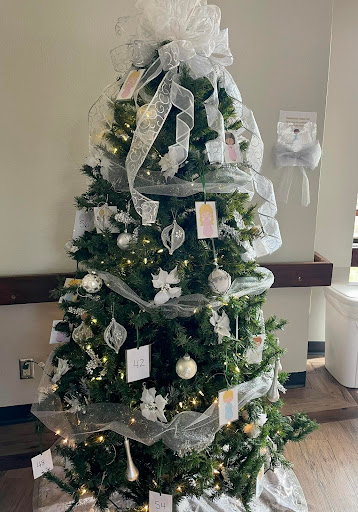 A beautifully decorated Christmas tree adorned with white ribbons and ornaments, bringing festive cheer to the space.