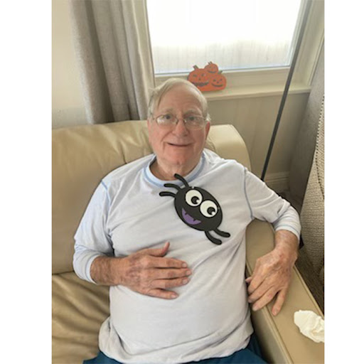 An elderly man with a playful spider graphic on his shirt, enjoying a moment of relaxation in his living room.