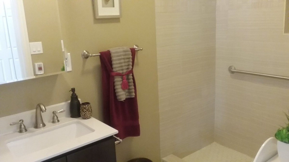 A modern bathroom with a neatly arranged towel, shower area, and sink.