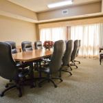 A spacious meeting room featuring a large conference table surrounded by office chairs.