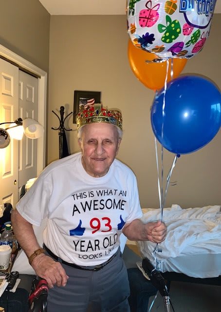 A joyful person celebrating their 93rd birthday with balloons and a crown.