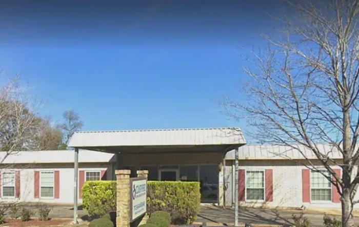 The image shows the entrance to a clinic with a clear blue sky in the background.