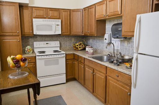 A cozy kitchen featuring wooden cabinets, a stove, and modern appliances.