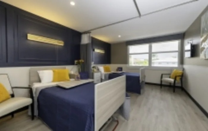A modern hospital room with two patient beds, featuring a stylish interior and comfortable amenities.