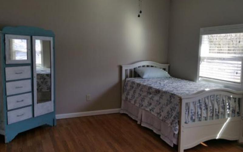 A minimalist bedroom with a single bed and a standing mirror.