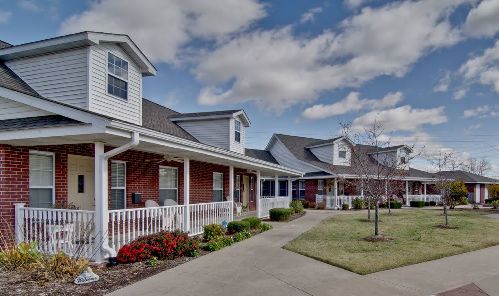 A charming residential building with a porch and a well-maintained lawn under a cloudy sky.