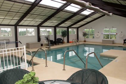 A serene indoor swimming pool area with a glass roof and seating.