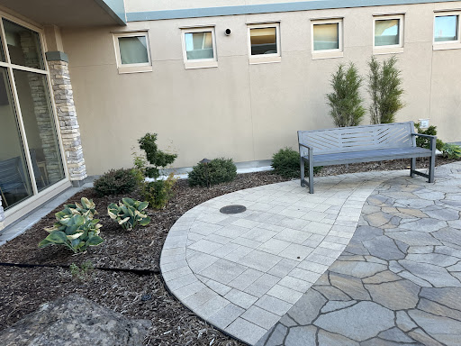 A serene outdoor space featuring a stone pathway, garden plants, and a bench for relaxation.