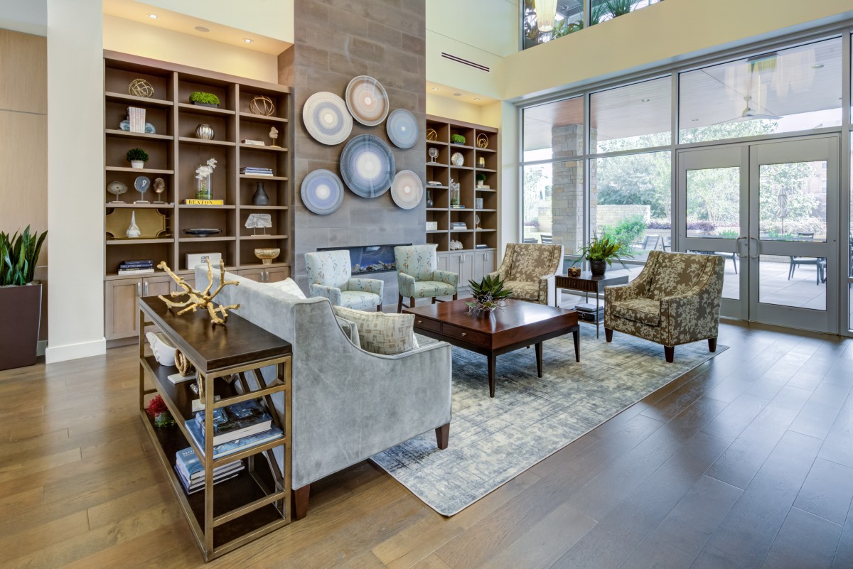 A cozy living room with elegant furniture and decorative elements, illuminated by natural light from large windows.
