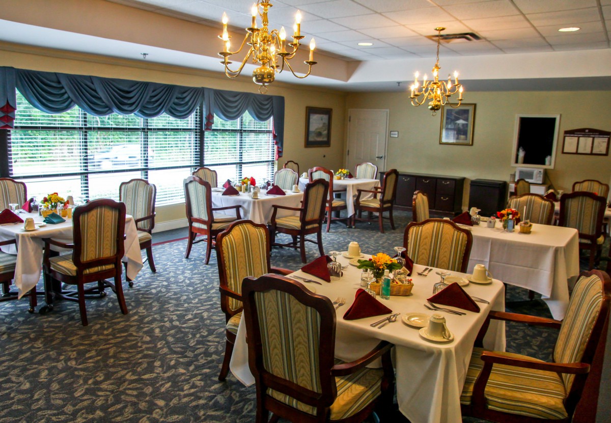 An elegant dining room with neatly arranged tables and chairs, adorned with chandeliers.