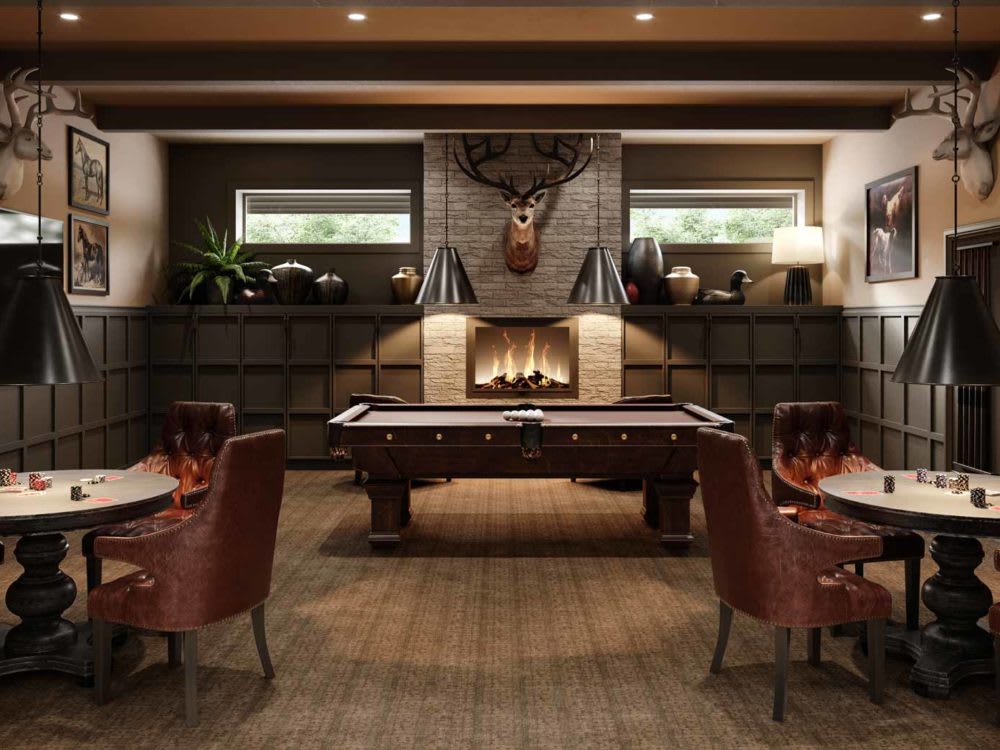 A cozy game room with a pool table and fireplace, featuring leather chairs and a mounted deer head.