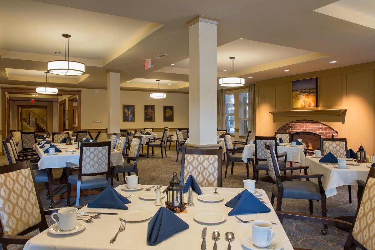 An elegant dining room with neatly set tables and blue napkins.