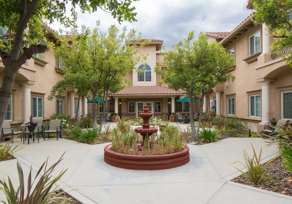 A tranquil courtyard featuring a central fountain surrounded by trees and outdoor seating.