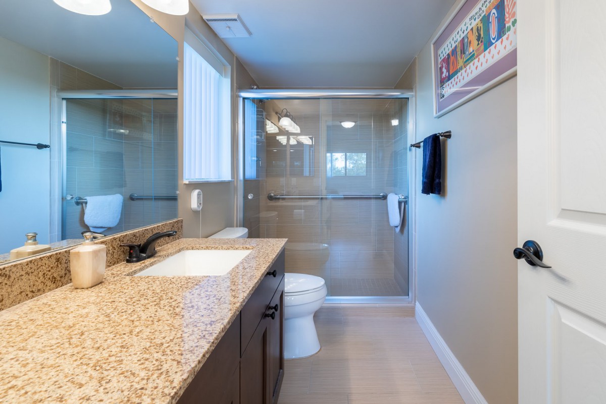 Modern bathroom with a granite countertop and glass shower enclosure.