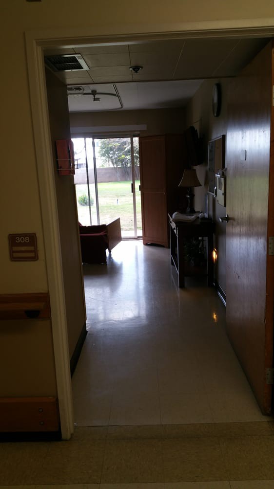 A view of a hospital room with a window overlooking an outdoor area.