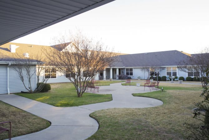 A peaceful courtyard with pathways, surrounded by a building and well-maintained landscaping.