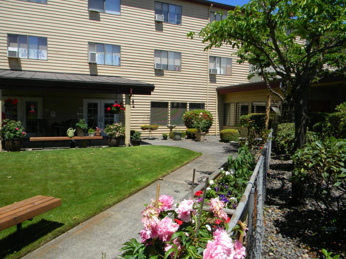 A well-maintained garden with colorful flowers in front of a building with multiple windows.